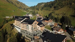 A mountainous village with traditional and modern buildings, a winding road, and a valley. - Apartment in Schrocken Near Ski Arlberg (Schroecken)