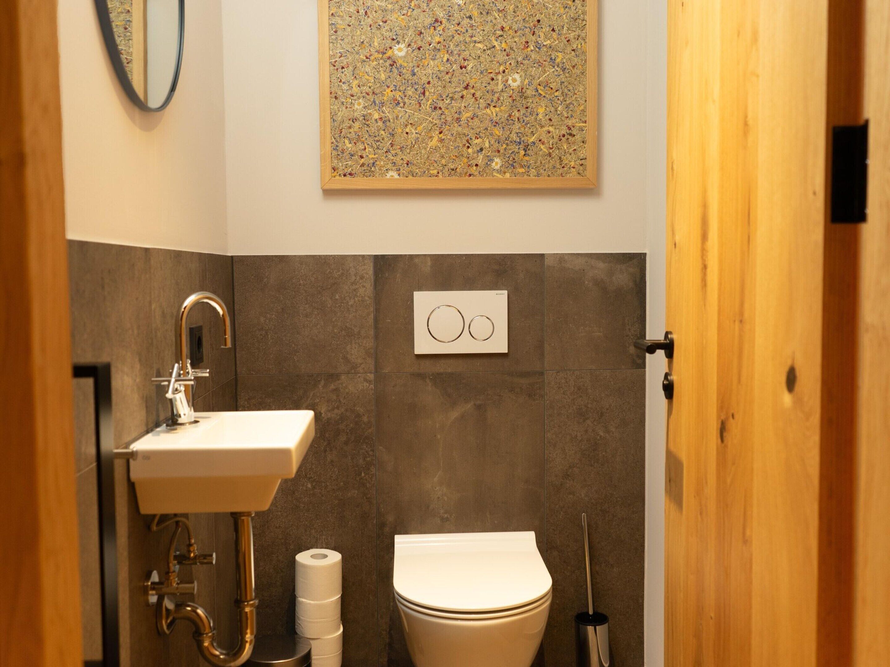 Un baño moderno con lavamanos, inodoro y un dispensador de papel higiénico de pared.