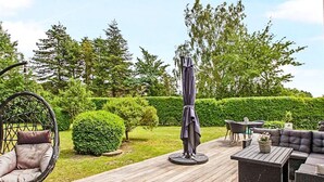 An outdoor patio with wicker furniture, a round table, and a cushioned chair.