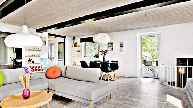 A modern living room with a grey sectional sofa, wooden coffee table, and pendant lights.