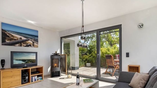 A modern living room with a large sofa, a flat-screen TV, a fireplace, and a sliding glass door to a patio. - Holiday Apartment Lore (Breege)