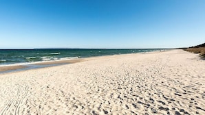 A wide sandy beach with footprints, a clear blue sky, and calm sea. - Holiday Apartment Lore (Breege)