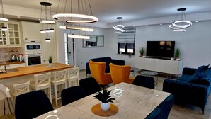 A modern kitchen with white cabinets, a wooden dining table, and a built-in oven. - Apartment in Croatia Near the Adriatic Coast (Malinska-Dubasnica)