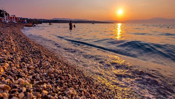 A pebbled beach with the sun setting over the water. - Apartment in Croatia Near the Adriatic Coast (Malinska-Dubasnica)