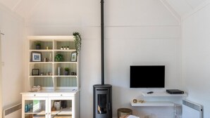 Una sala de estar moderna con un mueble blanco, una chimenea negra, un televisor de pantalla plana y un sofá negro.