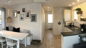 Une cuisine moderne dotée d’un îlot central, de meubles blancs et d’un coin repas avec une table et des chaises blanches.