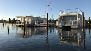 Une péniche amarrée, dotée d’une terrasse couverte et d’une petite cabine.