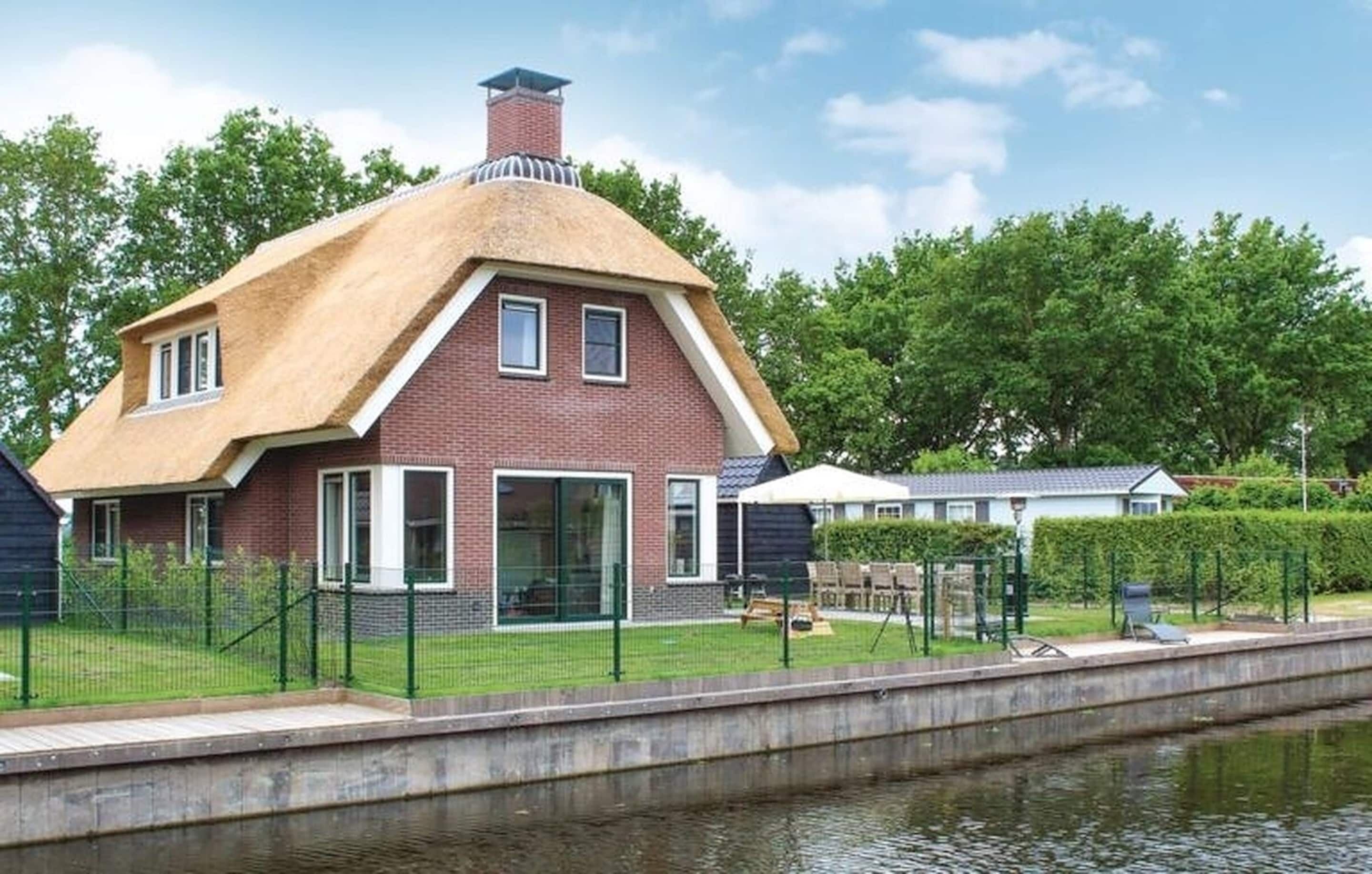 A house with a thatched roof, a brick exterior, and a small garden with a fence.
