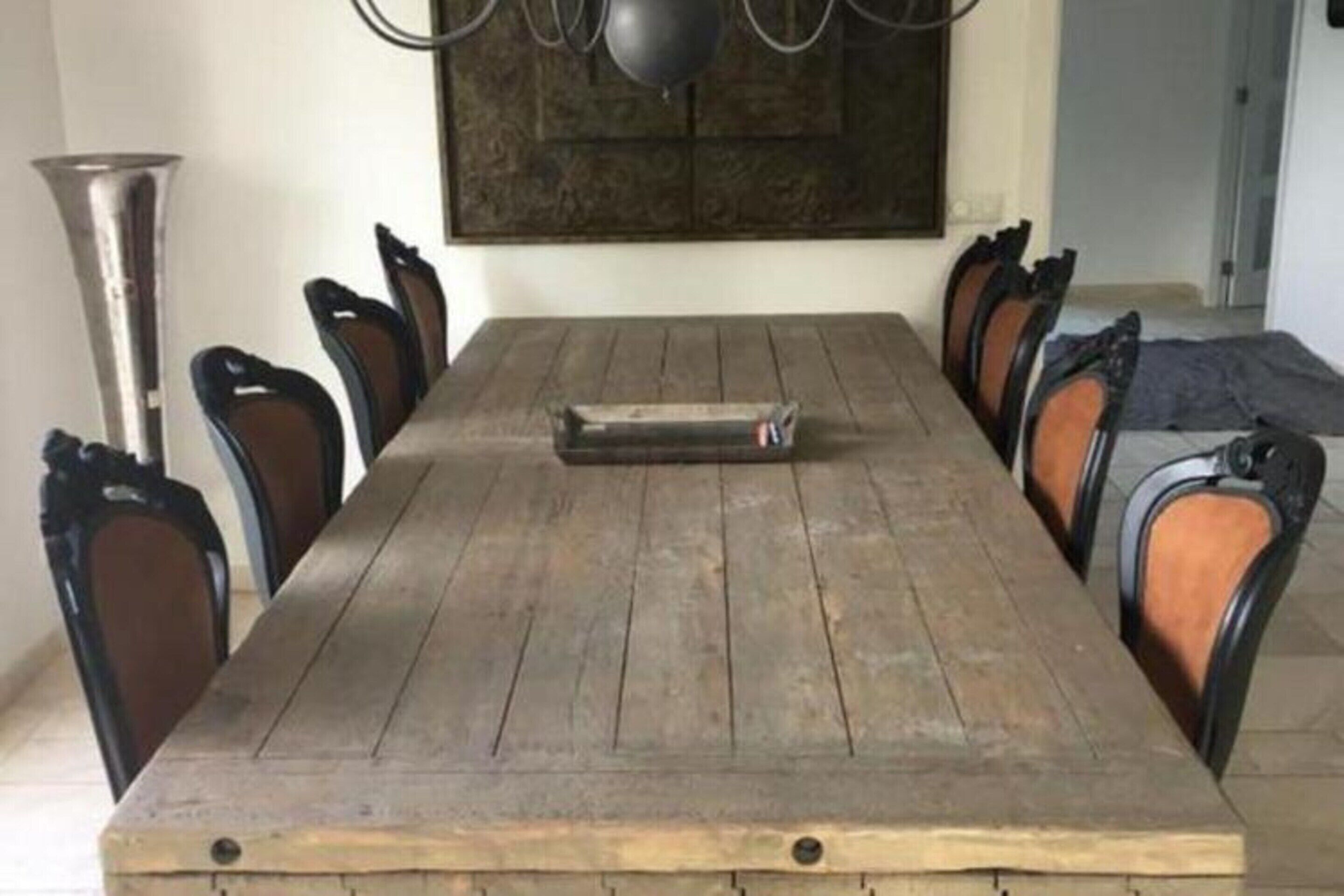 Une table à manger avec six chaises, un lustre et un élément décoratif mural.