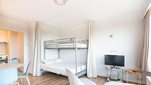 A modern hotel room with a bunk bed, a dining area with a table and chairs, a television, and a small radio. - Studio in Oostduinkerke With Sea View (Koksijde)