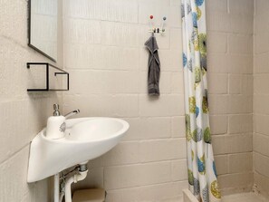 A bathroom with a white sink, a mirror, and a shower curtain with a leaf pattern. - 4 Person Holiday Home in Millinge (Millinge)