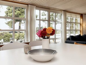 A dining area with a white table, a vase with flowers, and a bowl. - 4 Person Holiday Home in Millinge (Millinge)