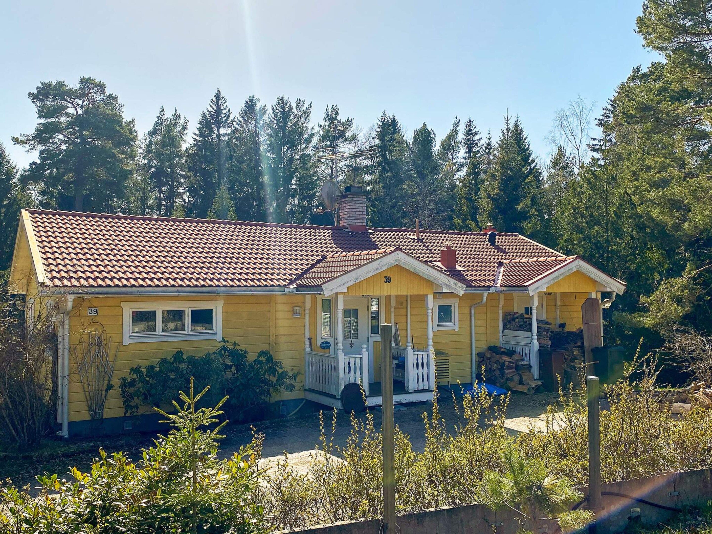 A yellow house with a red-tiled roof, number 39, surrounded by greenery.