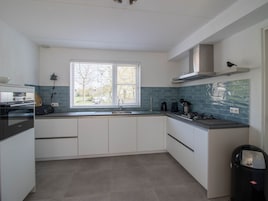 A modern kitchen with white cabinets, a stainless steel sink, and a window with blinds.