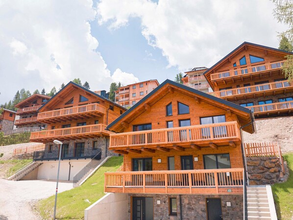 A multi-story wooden building with balconies, stone foundations, and a clear sky. - Cosy Studio With Terrace (Stadl-Predlitz)
