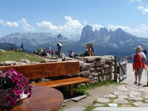 A mountain overlook with a wooden bench and a stone wall, overlooking rugged mountains and a clear sky. - Lovely Apartment in St. Ulrich in Groden (Ortisei)