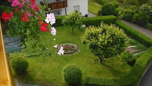 A well-maintained garden with a circular flower bed, neatly trimmed hedges, and a variety of shrubs. - Lovely Apartment in St. Ulrich in Groden (Ortisei)