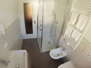 A compact bathroom with a glass-enclosed shower, a pedestal sink, and a bathtub. - Lovely Apartment in St. Ulrich in Groden (Ortisei)