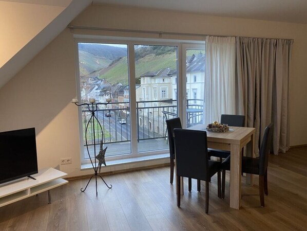 Una sala de estar moderna con un ventanal grande, una mesa de comedor y un mueble para televisión.