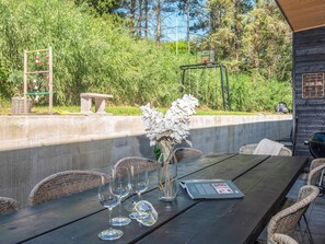 An outdoor dining area with wicker chairs and a table set with wine glasses and a menu. - 5 Star Holiday Home in Ebeltoft (Ebeltoft)