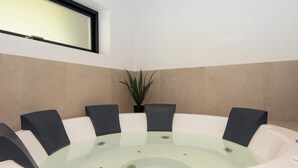 Een jacuzzi met acht stoelen, een potplant en een raam erboven.