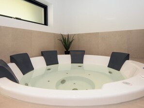 A hot tub with eight chairs, a potted plant, and a window above. - 5 Star Holiday Home in Ebeltoft (Ebeltoft)