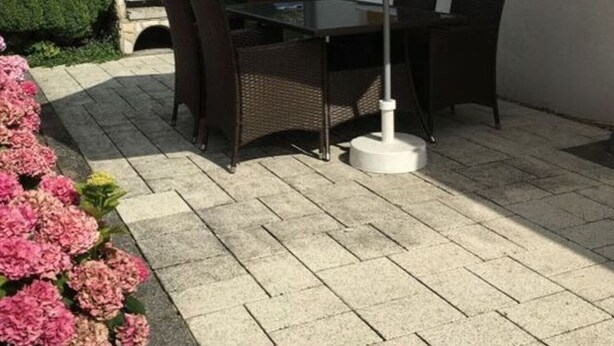 An outdoor patio with a table and chairs, a stone oven, and a white umbrella. - Holiday Home Steep Coast Fehmarn (Fehmarn)