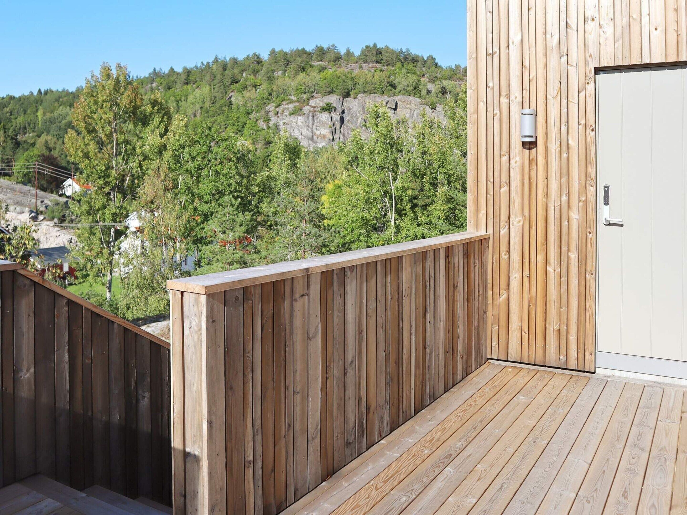 A wooden deck with a view of a forested hillside.