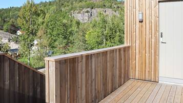 A wooden deck with a view of a forested hillside.