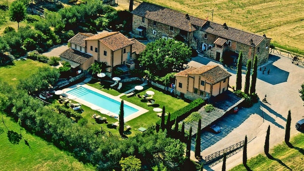 Vista aérea de una villa con piscina, rodeada de exuberante vegetación y un camino de piedra.
