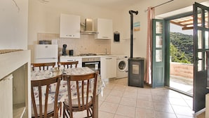 Una cucina compatta con angolo ristoro, lavatrice e un'ampia finestra vista sulla campagna.