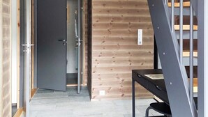 Un interior moderno con una pared de madera, una puerta oscura y una escalera.