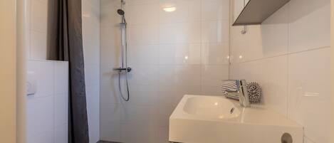 A modern bathroom with a shower, toilet, and sink.