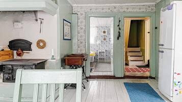 Una habitación con una mesa de comedor, sillas, un refrigerador y una escalera que lleva a otra estancia.