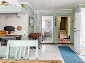 A room with a dining table, chairs, a refrigerator, and a staircase leading to another room. - 4 Person Holiday Home in Bjorko (Björkö)