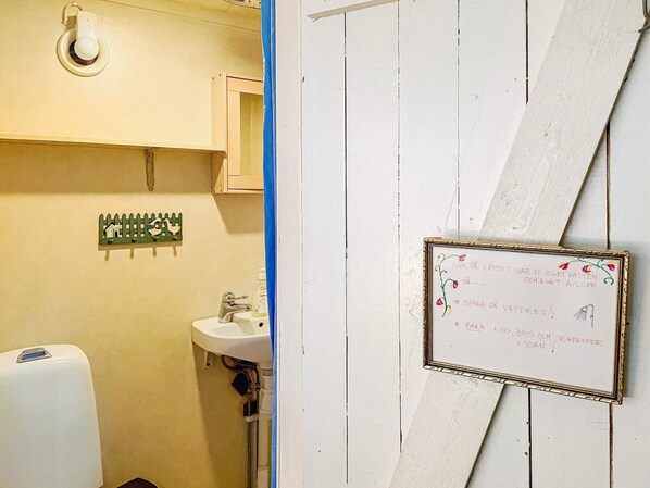 A bathroom with a sink, a toilet, and a hand dryer. There is a framed sign with text on the wall. - 4 Person Holiday Home in Bjorko (Björkö)