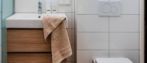 Un baño moderno con tocador de madera, inodoro blanco y calentador mural.