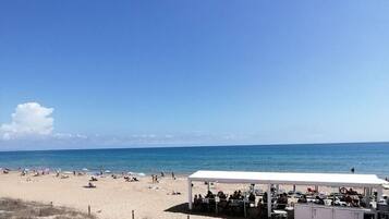 A beach with a white tented area, sandy dunes, and the ocean.
