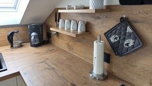 A kitchen with a wooden countertop, a coffee maker, a kettle, a paper towel dispenser, and a hanging oven mitt. - Shared Holiday in two Separate Flats (Brilon)