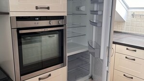 A kitchen with a built-in oven, a refrigerator with a freezer, and a countertop. - Shared Holiday in two Separate Flats (Brilon)