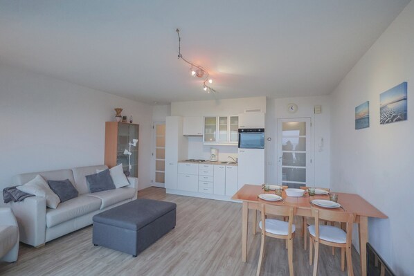 Cozy living space with a sofa set, dining table, and compact kitchen area.