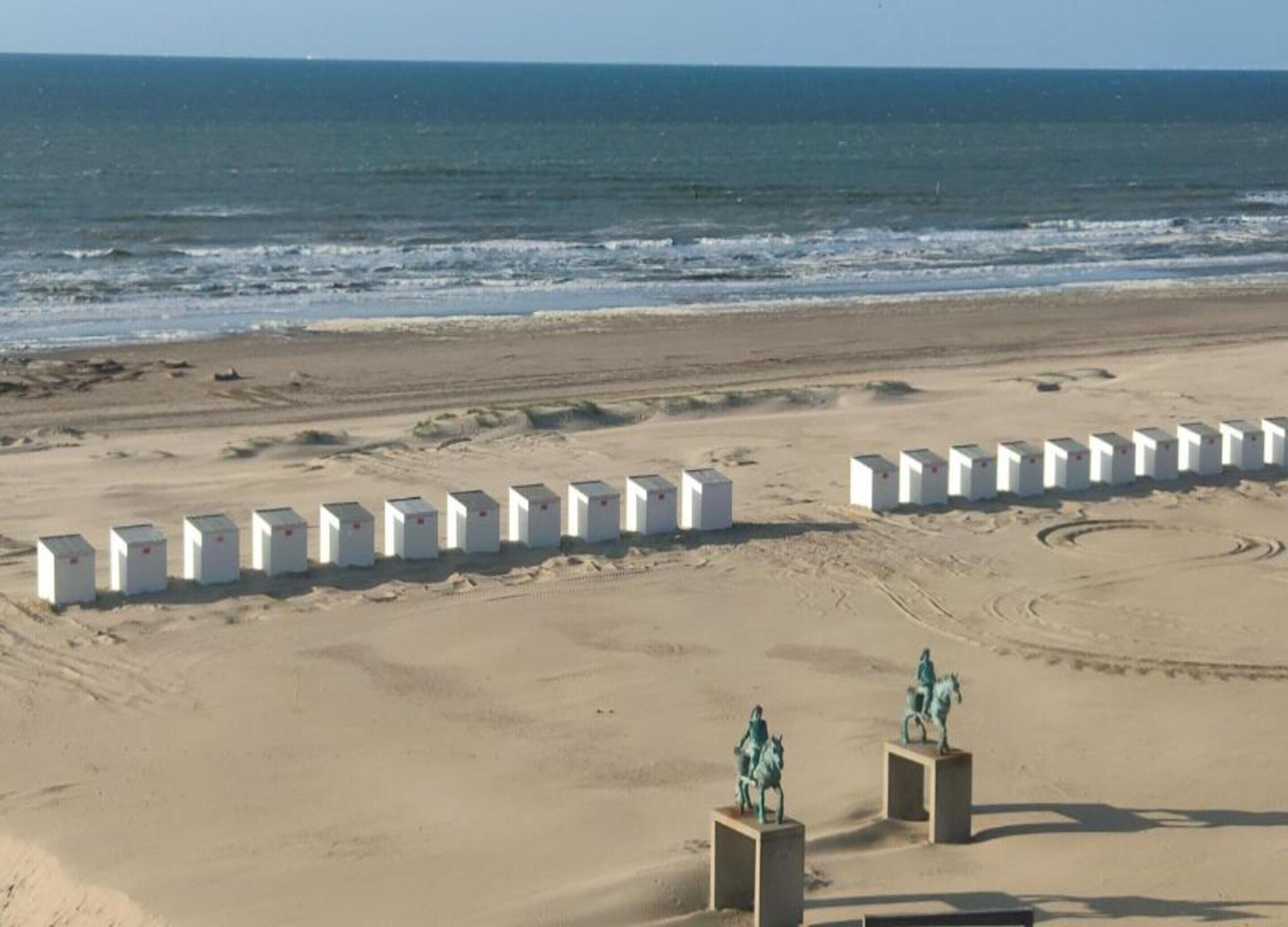Una spiaggia sabbiosa con strutture bianche e statue.