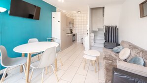 A modern living room with a sofa, a dining table with chairs, and a kitchen area in the background. - WELCS CASA ADOSADA 144 EMP con piscina comunitaria (Rosas / Roses)