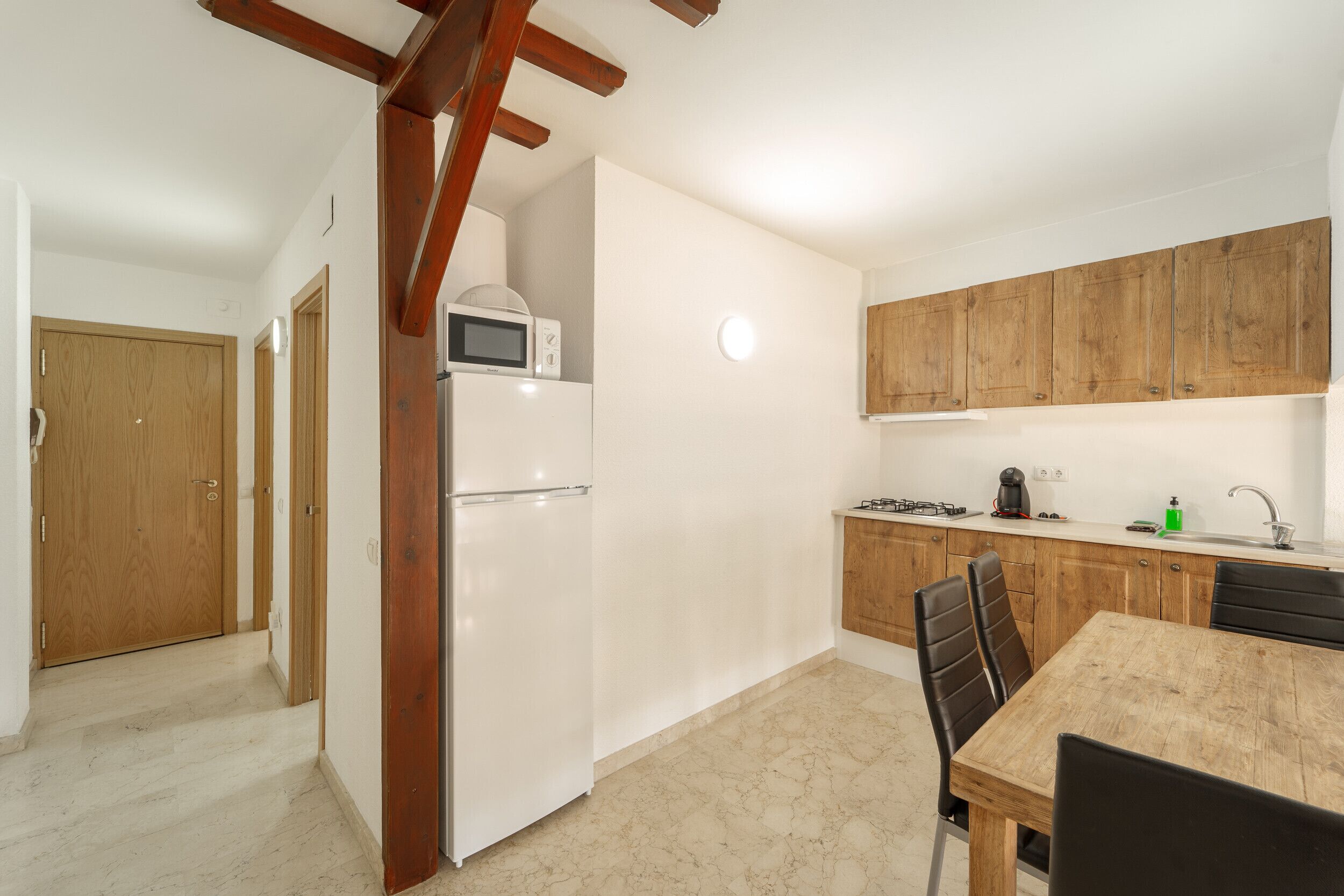 A compact kitchen with a refrigerator, microwave, and wooden cabinets.