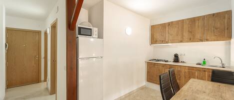 A compact kitchen with a refrigerator, microwave, and wooden cabinets.