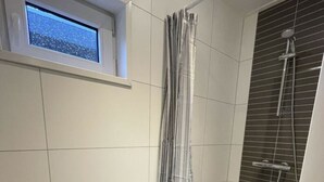 A bathroom with a window, a shower with a rain showerhead, and tiled walls. - Pavilion 4 People (Zorgvlied)