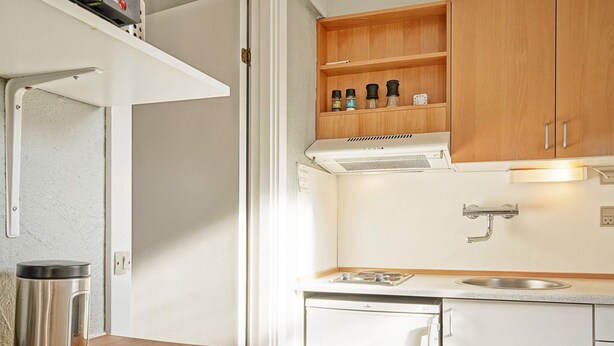 A compact kitchen with white cabinets, a stainless steel kettle, a sink, and a stove. - 4 Person Holiday Park Home in Gudhjem (Gudhjem)