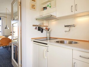 A modern kitchen with white cabinets, stainless steel appliances, and a window overlooking a garden. - 4 Person Holiday Park Home in Gudhjem (Gudhjem)