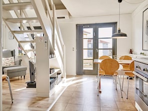 Eine moderne Küche mit Essbereich, Holzstühlen und einer Treppe, die zu einem Schlafgeschoss führt.