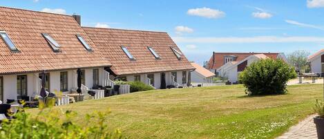 A row of houses with sloped roofs and skylights, a grassy lawn, and a paved walkway.